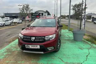 Vue 3/4 avant d'une Dacia Logan MCV rouge 2019 avec calandre noire et jantes alliage, stationnée sur un sol vert.