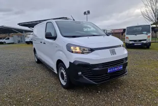 Fiat Scudo Fourgon blanc en 3/4 avant droit, avec calandre noire et plaque de protection, sur parking extérieur.