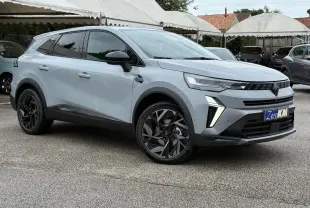 Renault Symbioz gris Rafale en vue 3/4 avant droit, avec jantes noires et feux LED distinctifs allumés.