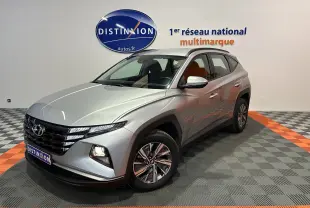 Vue 3/4 avant d'un Hyundai Tucson gris Shimmering Metal avec feux allumés dans un showroom.