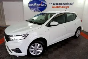 Vue 3/4 avant droite d'une Dacia Sandero Confort TCe 90 blanche, avec feux LED et jantes alliage visibles en intérieur showroom.