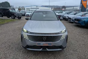 Vue avant d'un Peugeot 5008 gris métallisé 2025 avec calandre noire et feux LED en forme de griffes allumés.