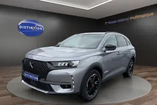 Vue 3/4 avant droit d'un DS7 Crossback gris clair avec calandre noire et jantes noires brillantes dans un showroom.
