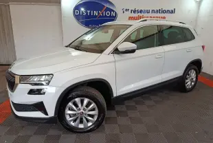 SKODA KAROQ blanc vue 3/4 avant droit en intérieur avec jantes argentées et barres de toit noires.