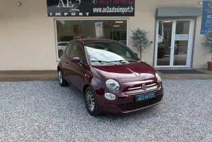 Fiat 500 violet vue 3/4 avant droit, berline compacte avec jantes alliage et calandre chromée devant un garage.