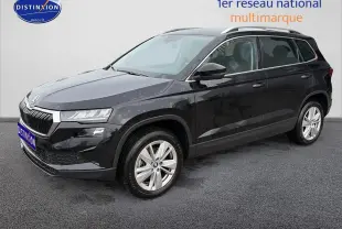 Vue 3/4 avant d’un Skoda Karoq noir 2025 avec jantes alu et barres de toit visibles sur fond neutre.