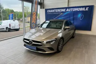 Mercedes Classe CLA 180 gris montagne métallisé vue 3/4 avant droit en showroom avec intérieur cuir beige visible