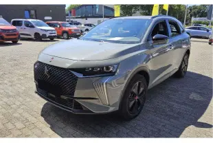 DS7 gris laqué vu en 3/4 avant droit, avec calandre noire texturée et jantes alliage noires distinctives.