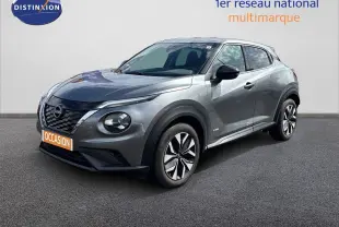 Nissan Juke Hybrid gris squale métal en 3/4 avant droit, avec jantes modernes et calandre noire distinctive.