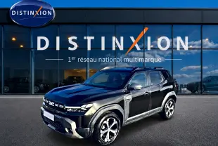 Dacia Duster noir vue 3/4 avant droit, avec jantes alu et barres de toit devant showroom Distinxion.