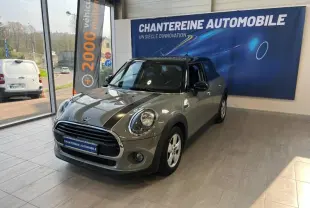 Vue 3/4 avant d'une MINI Cooper Moonwalk Grey avec bandes noires sur capot et toit noir en showroom.