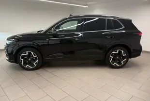 Vue de profil côté gauche du Volkswagen Tiguan 2025 noir intense nacré avec jantes R-Line distinctives en intérieur neutre.