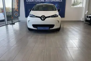 Vue frontale d'une Renault ZOE Zen charge rapide Q90 blanc nacré en showroom avec logo Renault bien visible sur la calandre.