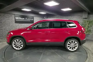 Profil droit d'un Skoda Karoq rouge avec jantes alliage 19 pouces dans un showroom intérieur.