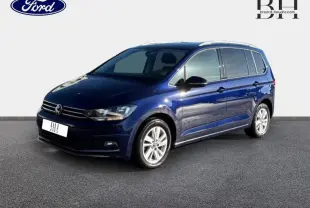 Volkswagen Touran bleu Atlantique métallisé vu en 3/4 avant droit avec jantes alu et barres de toit.