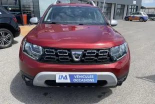 Vue avant d'un Dacia Duster rouge métal 2020 avec calandre noire et plaque "Véhicules Occasions" visible.