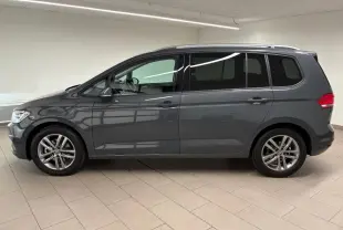 Profil droit d'un Volkswagen Touran 2025 gris dauphin avec jantes alliage et vitres teintées en intérieur neutre.