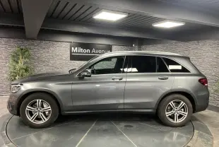 Vue latérale droite d'un Mercedes GLC gris métallisé avec jantes alliage 18 pouces dans un showroom intérieur.