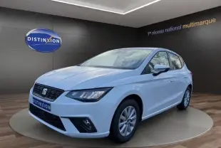 Vue 3/4 avant droite d'une SEAT Ibiza blanche 2023 avec vitres arrière surteintées et feux LED, sur fond showroom.