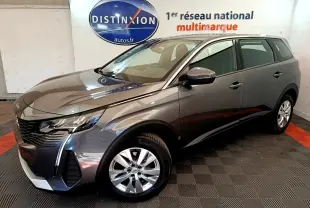 Peugeot 5008 gris clair vue 3/4 avant droit, avec jantes alliage et feux LED, en intérieur showroom.