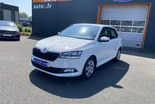 Vue 3/4 avant droite d'une Skoda Fabia blanche 2021 garée devant un bâtiment commercial.