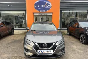 Nissan Qashqai gris Squale vu de face, garé devant un concessionnaire avec logo orange Distinxion.