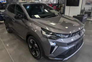 Vue 3/4 avant droite du Renault SYMBIOZ E-TECH Full Hybrid gris Cassiopé avec jantes bi-ton et calandre moderne en showroom.