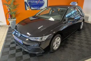 Volkswagen Golf 1.5 eTSI Style noire vue en 3/4 avant droit dans un showroom avec mur orange.