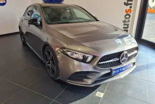 Mercedes Classe A 180 AMG Line gris vue 3/4 avant droit en intérieur, avec calandre diamant et jantes noires biton.
