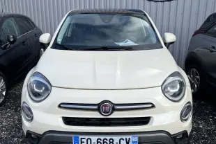 Vue frontale d'un FIAT 500X beige de 2020 garé devant un mur métallique avec un panneau Distinxion visible.