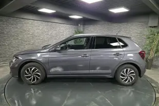 Profil côté gauche d'une Volkswagen Polo gris métallisé 2025 avec jantes alliage et vitres arrière surteintées dans un showroom.