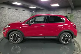 Vue latérale droite d'un Fiat 500X rouge Passione avec jantes alliage 17 pouces et vitres surteintées.