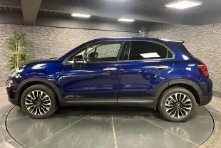 Profil latéral droit d'une Fiat 500X bleu métallisé avec jantes alliage 17 pouces dans un showroom.