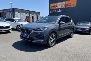 SEAT Tarraco gris dauphin vu en 3/4 avant droit sur un parking avec jantes alliage et toit panoramique.
