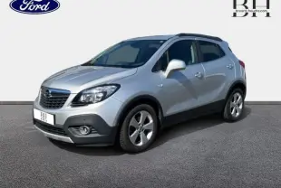 Opel Mokka gris minéral vue 3/4 avant droit avec jantes alliage et barres de toit noires.
