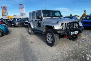 Jeep Wrangler gris clair vue 3/4 avant droit avec étoile noire sur porte et pare-buffle équipé de phares additionnels.
