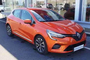 Renault Clio 1.6 E-Tech hybride orange Valencia vue 3/4 avant droit, avec jantes alliage et feux LED distinctifs.