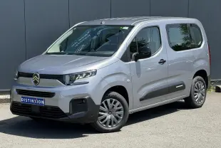 Vue 3/4 avant droit du Citroën Berlingo ë-136 gris Artense avec jantes tôles et protections latérales noires.