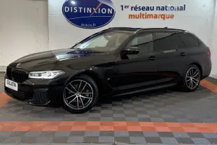 BMW Série 5 Touring 520d noir vue de profil droit en intérieur avec jantes M Sport et phares LED allumés.