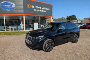 BMW X1 XDrive 20d noir métallisé en 3/4 avant droit, avec jantes alliage et calandre chromée M Sport visible.