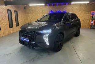 DS7 E-TENSE gris en 3/4 avant droit, avec calandre distinctive et feux LED en forme de flèche allumés.