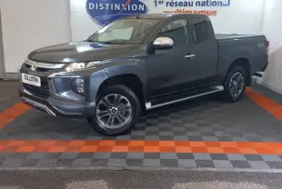 Mitsubishi L200 gris foncé en 3/4 avant droit, avec benne pick-up et jantes alliage visibles en intérieur showroom.
