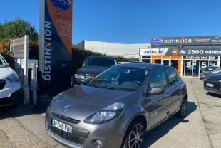 Renault Clio III gris métallisé vue 3/4 avant droit sur un parking devant un concessionnaire Distinxion.