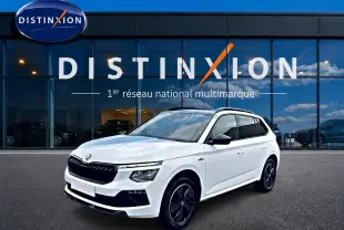 SKODA KAMIQ blanc nacré en 3/4 avant, avec jantes noires et toit panoramique visible devant une vitrine Distinxion.