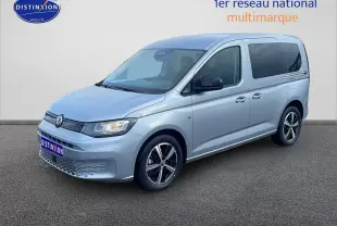 Volkswagen Caddy gris argent vu en 3/4 avant droit, avec jantes alliage et vitres arrière teintées.