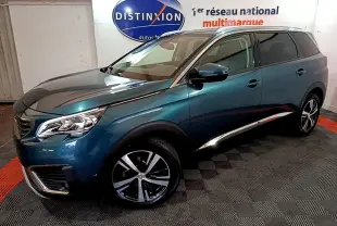 Peugeot 5008 bleu en 3/4 avant droit, avec jantes alliage et calandre distinctive dans un showroom.