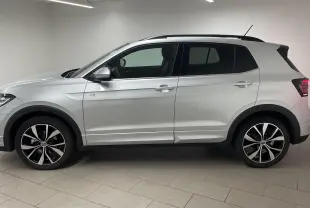 Profil côté gauche du Volkswagen T-Cross 1.0 TSI R-Line 2025 en peinture métallisée reflet d'argent avec jantes alliage 18 pouces.