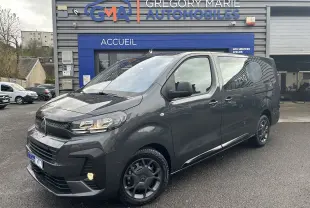 Vue 3/4 avant droit d’un Citroën Jumpy Cabine Approfondie gris titane métallisé garé devant un garage automobile.