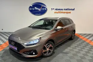 Vue 3/4 avant droit d'une Hyundai i30 SW 2022 couleur bronze métallique avec phares LED allumés en showroom.