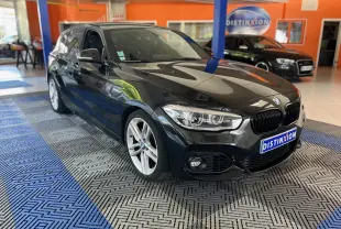 BMW Série 1 118i M Sport noir vue 3/4 avant droit en intérieur avec jantes argentées et calandre noire.